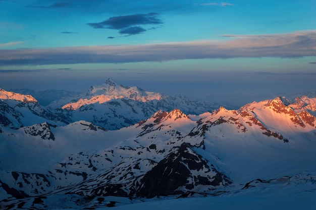 Golden sunset lights snowy peaks of Caucasus Range Majestic mountain landscape glow at dusk Clear