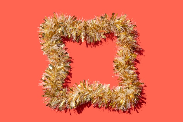 Golden tinsel frame on a coral red background for Christmas card