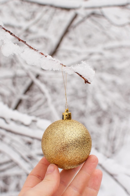 Golden toy ball in hand on a blurry winter background