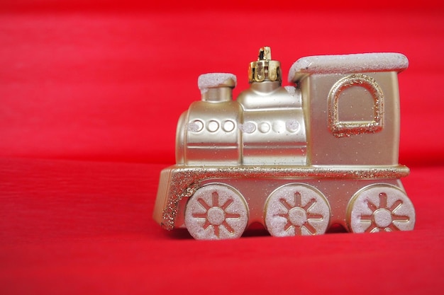 Golden toy train locomotive on a red and pink gradient background New Year or Christmas card Icicles and snow on a train Free space for text Copy space Festive background