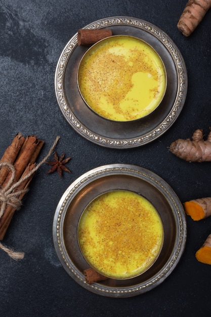 Golden turmeric milk on black with ingredients