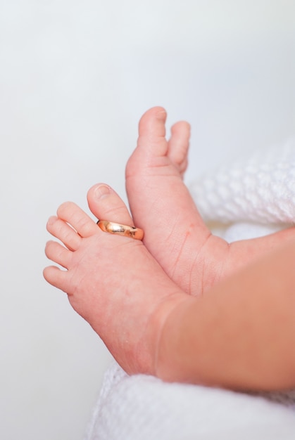 Golden wedding ring on the thumb of small children s legs on a white background.