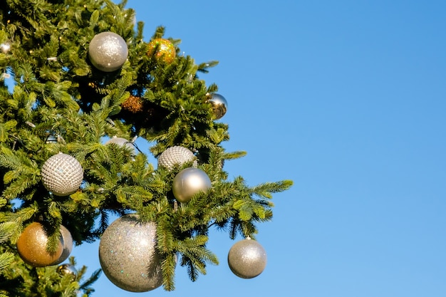 Golden and white New Year decorations and garland on a Christmas tree outdoors