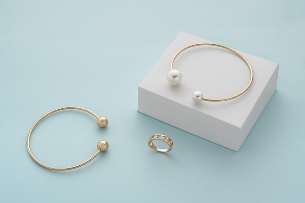 Golden with pearls bracelet on white box and gold bracelet and ring with copy space