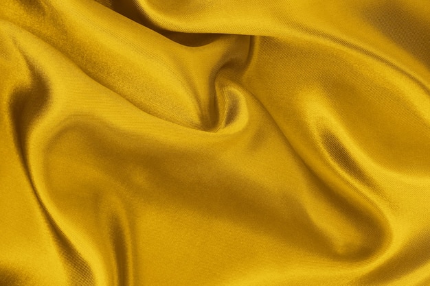 Golden yellow fabric texture background crumpled pattern of silk or linen