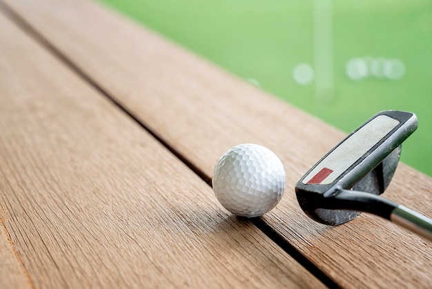 Golf ball and golf club on wooden table