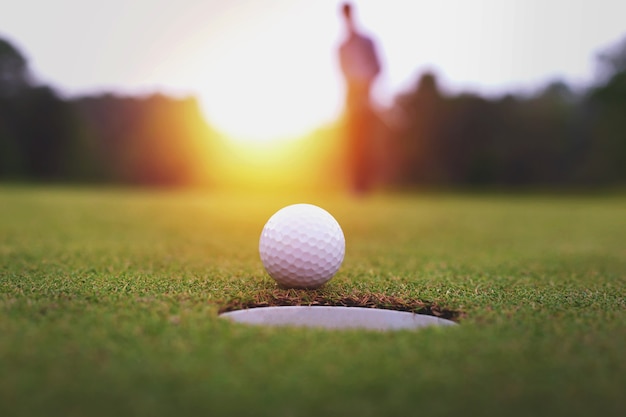 Golf balls and golf club on green grass shiny light sunse