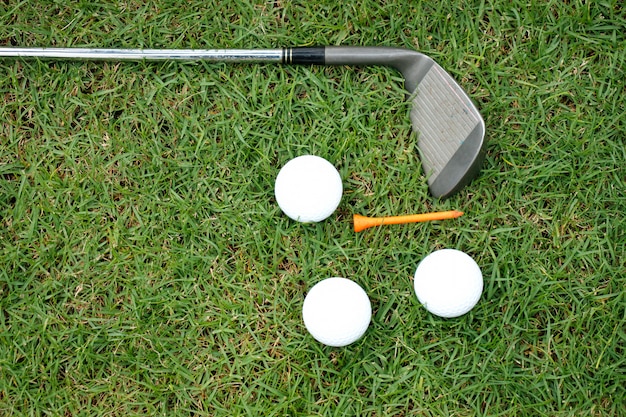 Golf club and golf balls on green grass