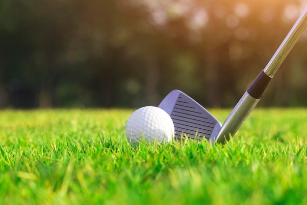 Golf clubs and golf balls on a green lawn in a beautiful golf course