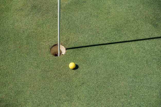 Golf field with yellow ball near the hole