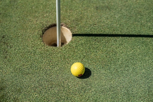 Golf field with yellow ball near the hole