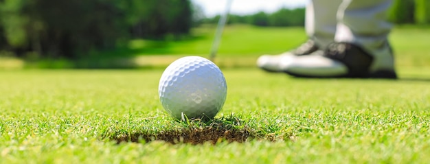 Golf player at the putting green hitting ball into a hole