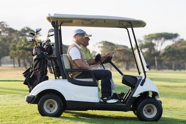 Golfer friends sitting in golf buggy