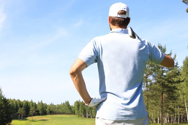 Golfer hits an fairway shot towards the club house.