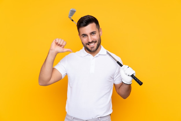 Golfer player man over isolated yellow wall proud and self-satisfied