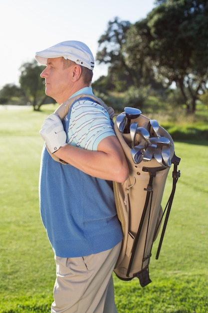 Golfer standing holding his golf bag