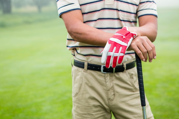 Golfer standing and leaning on his club 