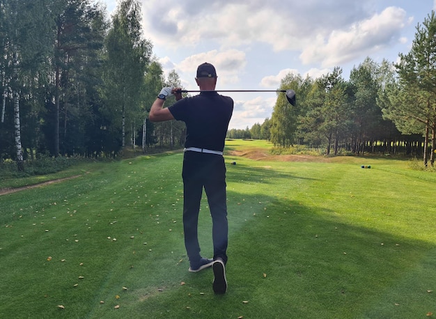 Photo a golfer taking a swing on a sunny day at a forest golf course