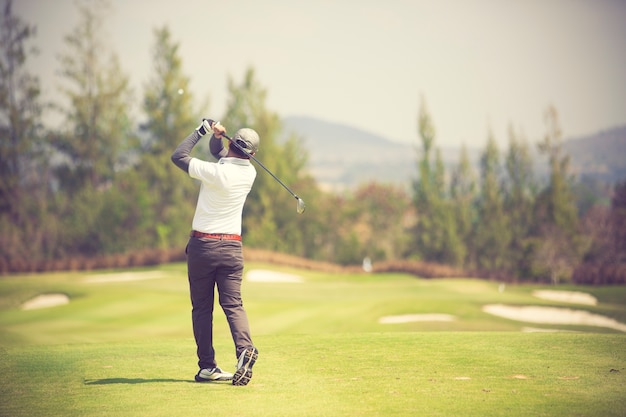 Golfers hit sweeping golf course in the summer vintage color