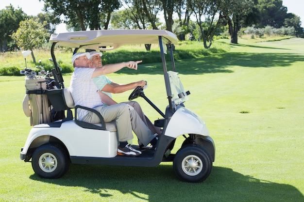 Golfing friends driving in their golf buggy