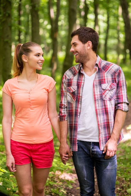 Good day to walk in park. Beautiful young loving couple walking in park and holding hands