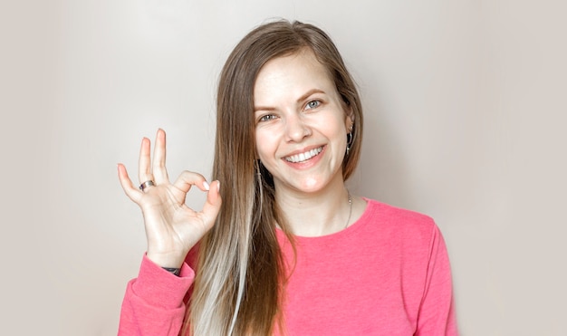 Good job. Pretty carefree modern stylish caucasian girl long chestnut hair show okay ok approval sign smiling toothy tilting head pleased give positive reply like excellent service, white background