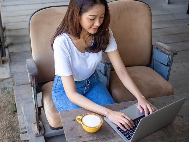 Good looking Asian women use computers to connect to the internet to communicate with foreign friends A happy and relaxed woman is sitting on the sofa Working woman and freelance concept