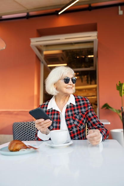 Good looking pensioner female relaxing at street cafe