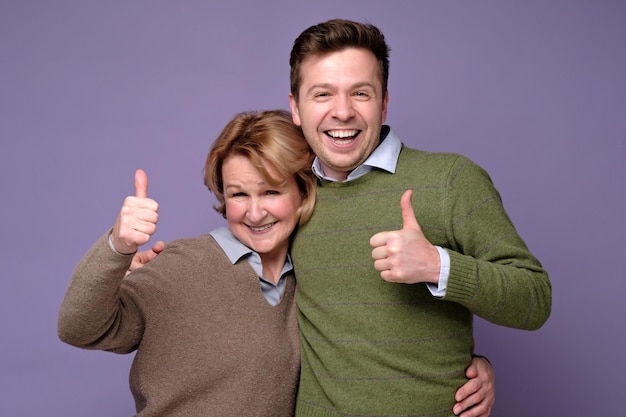 Good looking smiling man and woman mother and son showing OK sign with two hands