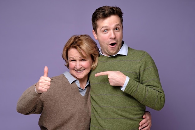 Good looking smiling man and woman mother and son showing OK sign with two hands