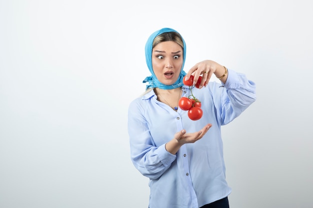 Good-looking woman in blue shawl holding red fresh tomatoes