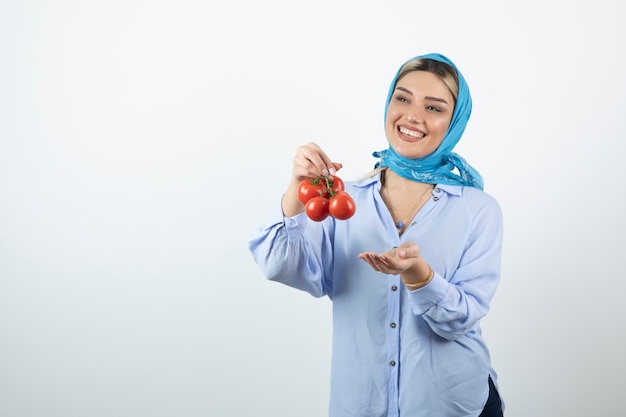 Good-looking woman in blue shawl holding red fresh tomatoes