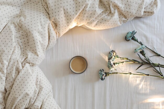 Good morning cozy composition with coffee cup blue flowers in bed