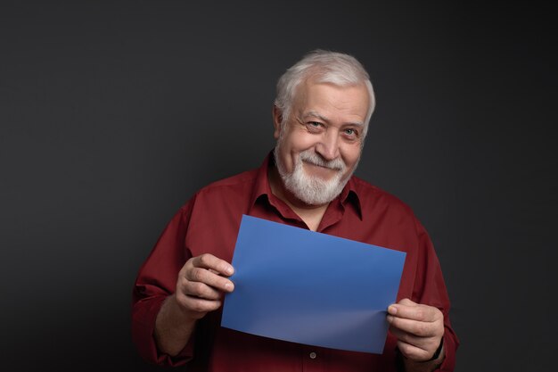 Good-natured smiling man holding a sheet of blue paper for the inscription