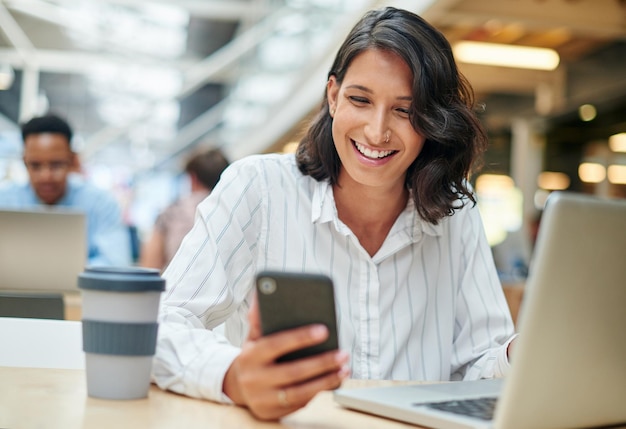 And the good news keeps rolling in Shot of a young businesswoman using a laptop and smartphone in a modern office