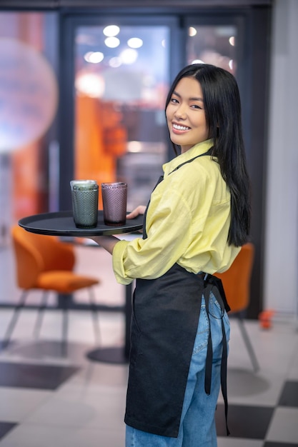 Good service. Young asian waitress with a tray in hands