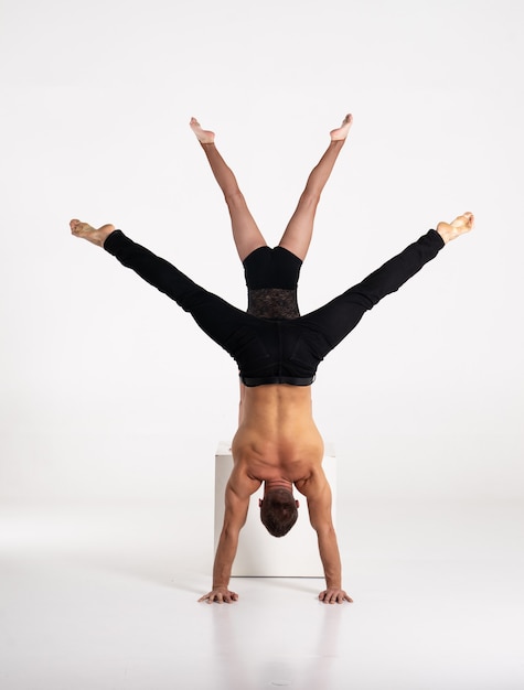 Good shaped man and woman practicing handstand exercise isolated on white background. Strength and motivation.