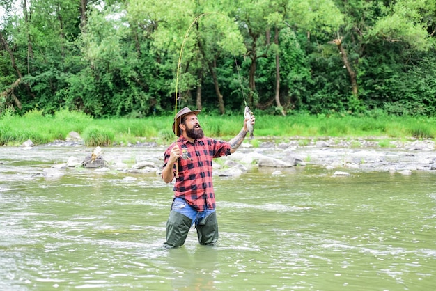 Good things for Good Moments hobby and sport activity bearded fisher in water fisherman show fishing technique use rod mature man fly fishing man catching fish summer weekend Happy fly fishing