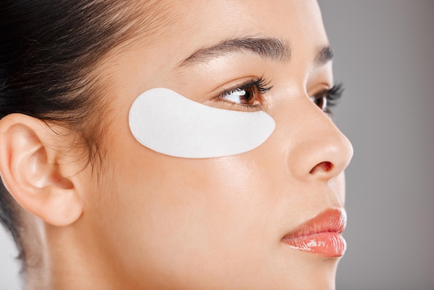 Goodbye under eye darkness hello glow Studio shot of an attractive young woman wearing an under eye patch against a grey background