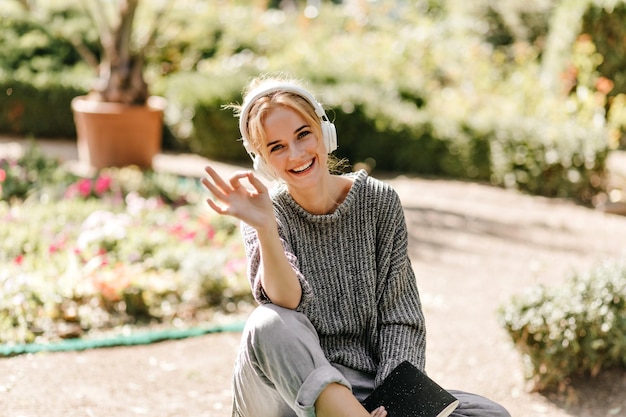 Goodhumoured female student holding her notes and laughing Outdoor portrait of debonair girl having fun in sunny autumn day