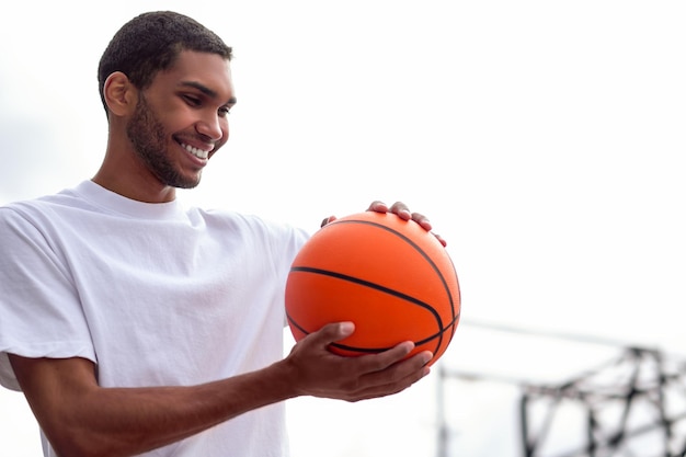 Goodlooking young man in white tshirt smiling and holding a ball