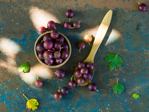 Gooseberries in a bowl on an old surface leaves and berries of red and green gooseberries