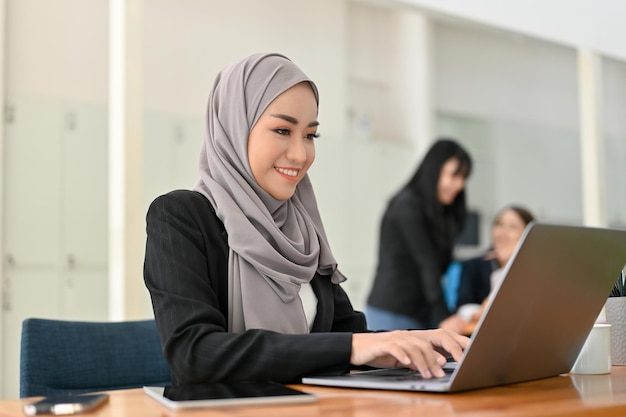 Gorgeous Asian Muslim businesswoman working on the laptop at her office desk in the office