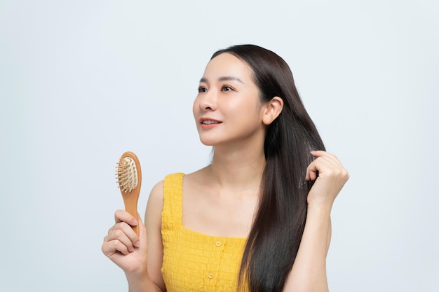 Gorgeous asian woman brushing her healthy hair