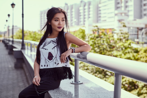 Gorgeous asian woman in fashion dress posing on bright street