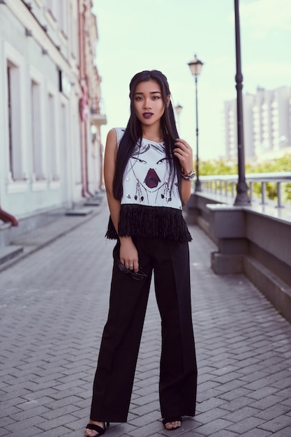 Gorgeous asian woman in fashion dress walking along bright street