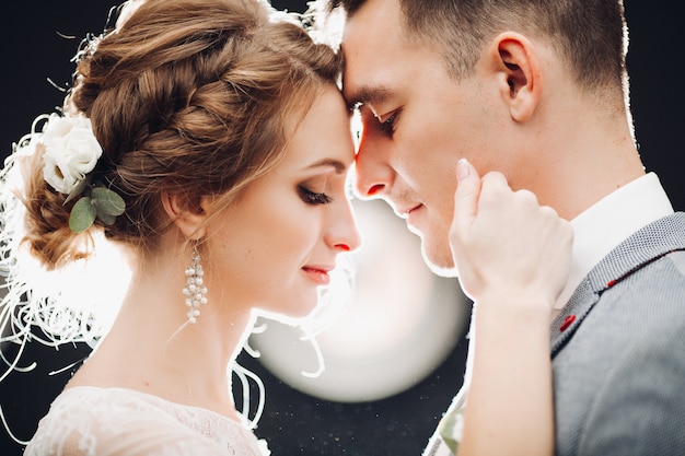 Gorgeous bride and handsome groom touching by faces each other