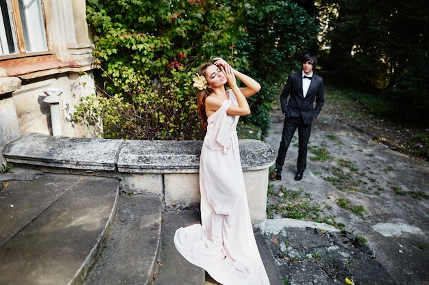 Gorgeous bride with long curly hair in wedding dress standing at park background, wedding photo.