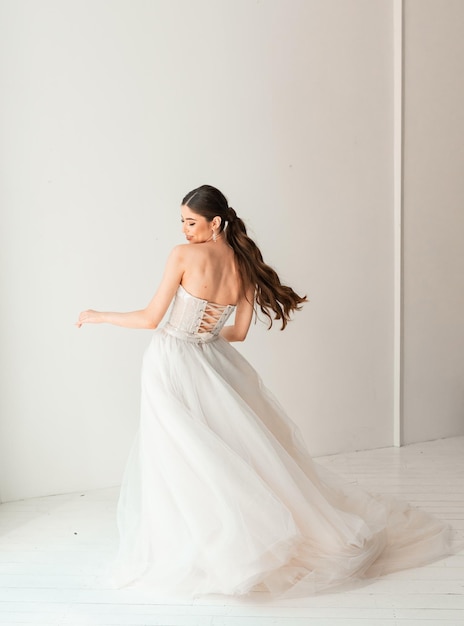 Gorgeous brunette bride in a white luxurious dress posing