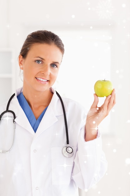 Gorgeous brunette doctor looking at a green apple